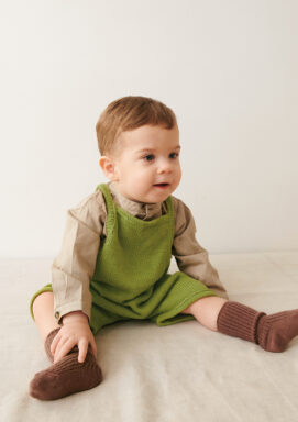 Liten bebis som sitter ner och bär grön Bunny Shorts Baby stickad i Sandnes Mandarin Petit Matcha 9564 i mönster för barn från Sandnes Garn.