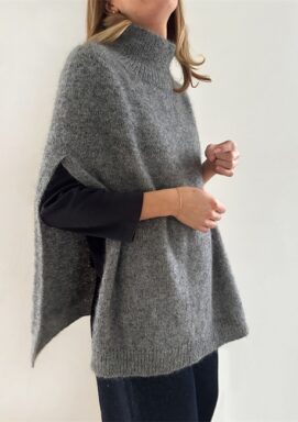 Kvinna som bär långärmad svart tröja med grå cape över stickad i mönster Darcy Capy från Le Knit.