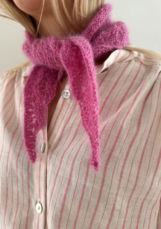En kvinna har en rosa stickad scarf knuten runt sin hals