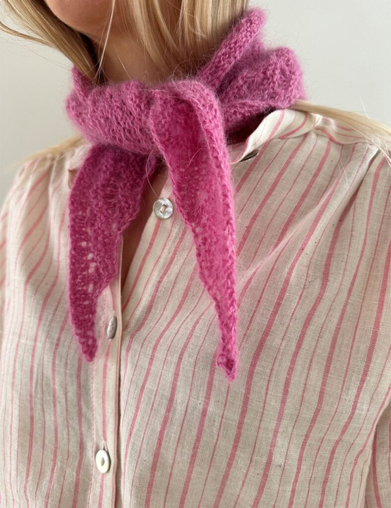 En kvinna har en rosa stickad scarf knuten runt sin hals