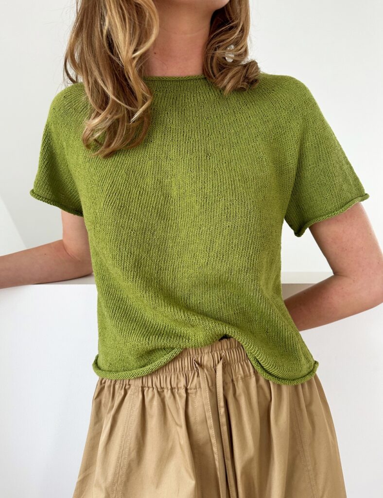 kvinna med en grön stickad t-shirt lite instoppad i ett par beiga linnebyxor