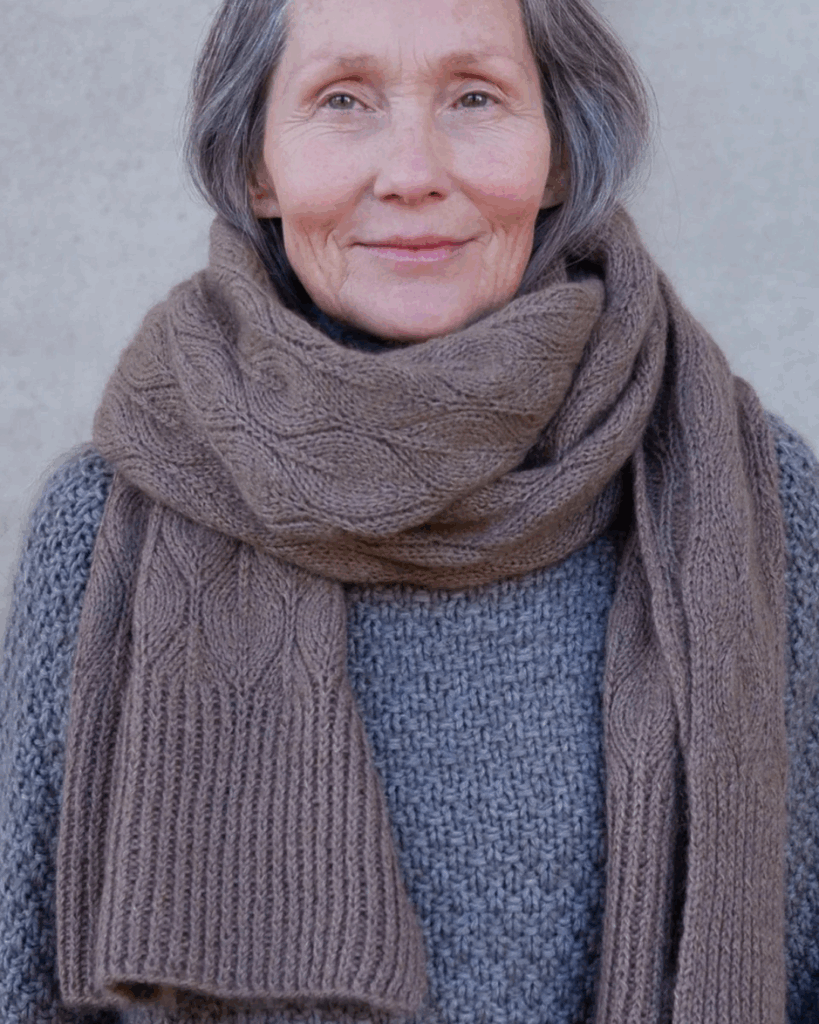 Kvinna med halsduk stickad i mönster Olive Scarf