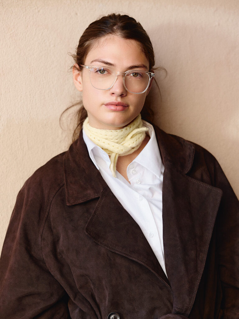 kvinna med mörk rock med vit skjorta under har en ljusgul stickad scarf knutan runt halsen